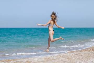 Fototapeta na wymiar Tall slim girl runs in direction of the sea