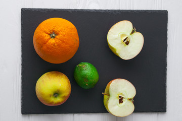 avocado ,apple orange and lime on stone board 