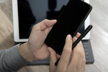 Hand using mobile payments online shopping,omni channel,icon customer network,in modern office wooden desk, blank interface screen