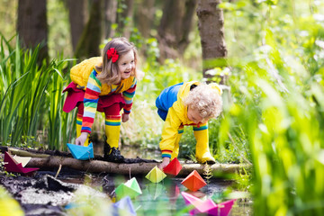 Kids playing with colorful paper boats in a park