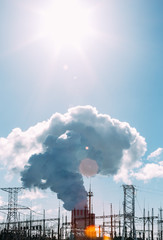 Thick white smoke from the chimney of a nuclear power plant. High-voltage wires 