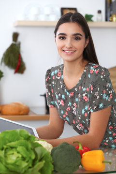 Young hispanic  woman is making online shopping by tablet computer and credit card. Housewife found new recipe for  cooking in a kitchen