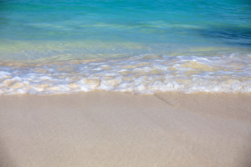 Fototapeta na wymiar Close up blue sea water waves with bubbles on sand beach