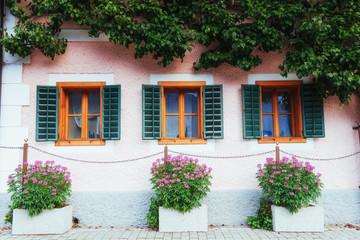 Fototapeta na wymiar Typical Austrian Alpine house with bright flowers on the balcony