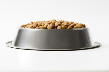 dry pet food in a metal bowl isolated on white background