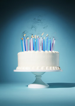 Birthday cake with lit candles against blue background