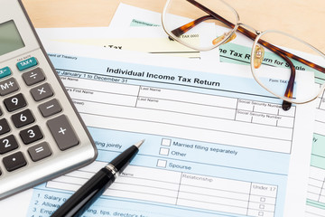 Tax form with calculator, pen, and glasses; document are mock-up