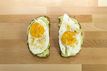 Avocado toast and fried egg on wooden background for breakfast