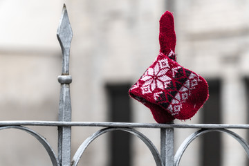 Red patterned ethnic glove / mitten / attached on the sharp, metal, fence spike.