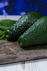 Green ripe avocado with leaves on granite plank