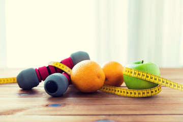 close up of dumbbell, fruits and measuring tape