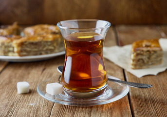 Glass of Turkish black tea with baklava on a wooden background