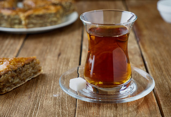 Glass of Turkish black tea with baklava on a wooden background