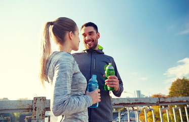 smiling couple with bottles of water outdoors