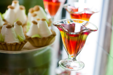 Red yellow jelly in glass cup, citrus fruit gelatin dessert, cake background. macro soft focus