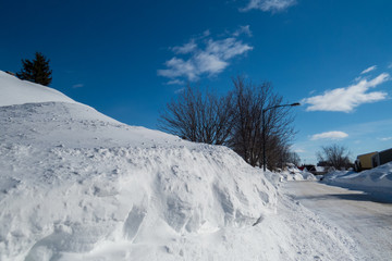 Huge snowbank plowed from the street after many winter storms taken during a beautiful winter day....