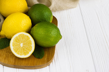 Lemons and limes on white wooden table.