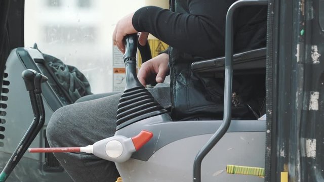 Driver in yellow excavator cabin pulling switches roating it around. Close up