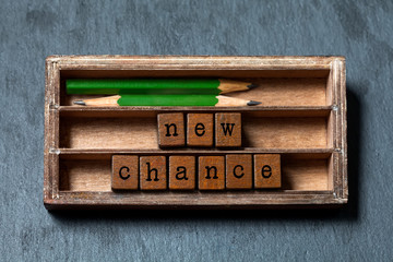 New chance phrase. Motivation and positive expectations concept. Vintage box, wooden cubes with old...