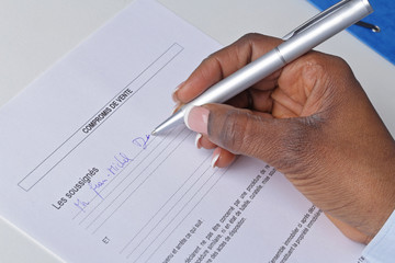 main femme noire signant un compromis de vente maison