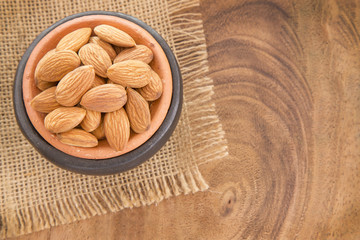 Almonds in bowl on wooden background