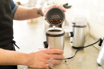 Pouring coffee grains on a grinder
