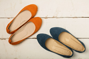 Blue and orange women's shoes (ballerinas) on wooden background.