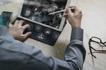 Designer Businessman hand using smart phone,mobile payments online shopping,omni channel,digital tablet docking keyboard computer in modern office on wooden desk,virtual interface icons screen