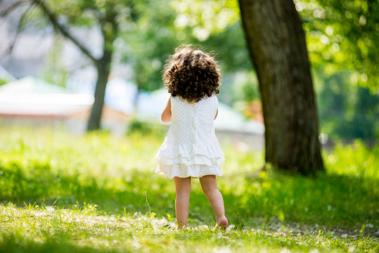 Little curly girl walking in the park