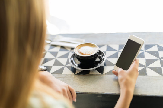 Using a smartphone and drinking coffee