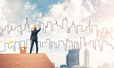 Man architect draw silhouette of modern city on blue sky. Mixed 