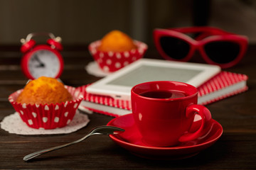 Cup of coffee and cupcakes, notepad and e-book.