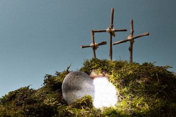 resurrection garden as easter decoration with a stone near the empty tomb filled with blinding light and three crosses on a hill above © what4ever