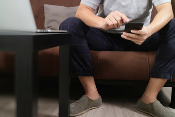 hipster hand using digital tablet docking keyboard and smart phone for mobile payments online business,omni channel,sitting on sofa in living room