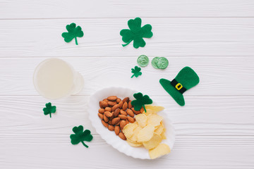 Traditional Irish St. Patrick's Day symbols hat, beer,clover leafs and coins on wooden background