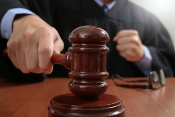 justice and law concept.Male judge in a courtroom striking the gavel,working with digital tablet computer docking keyboard on wood table