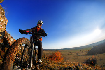Plakat low angle view of cyclist riding mountain bike on rocky trail at sunrise