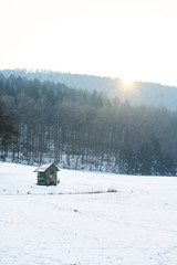 wooden cabin in the field with snow in winter, white