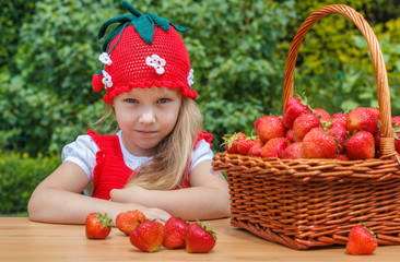 A funny little girl 4 years old with a basket of strawberries