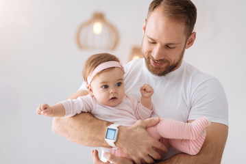 Careful young father holding his newborn at home