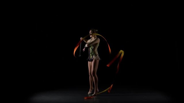 Flexible gymnast with tape creates beautiful hands graceful movements. Black background