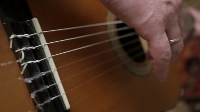 Caucasian man plays acustic guitar. Close up handheld shot