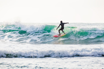 Surfing and blue wave in ocean. Surfing in wetsuit