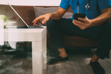 Medical and Health context,doctor hand working with smart phone,digital tablet computer,stethoscope,sitting on sofa in living room