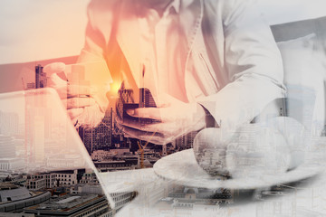 double exposure of hipster hand using smart phone,digital tablet docking keyboard,holding credit card payments online business,sitting on sofa in living room,work at home,London architecture city