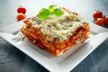 Homemade Crispy lasagna in iron pan with minced beef bolognese sauce, parmesan cheese and basil