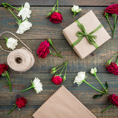 Pattern with roses, gift box, craft paper and twine on wood background. Workspase. Flat lay, top view. Woman background