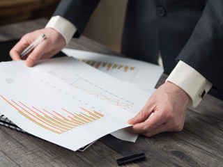 Business man hold a pen checking bar chart