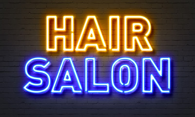 Hair salon neon sign on brick wall background.