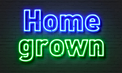Home grown neon sign on brick wall background.